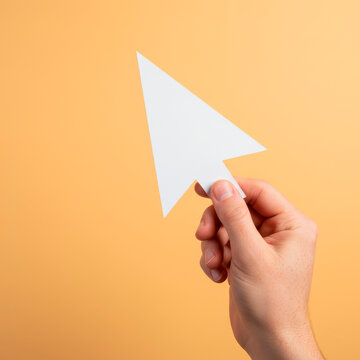 Hand holding paper mouse cursor symbolizing digital interaction in creative environment