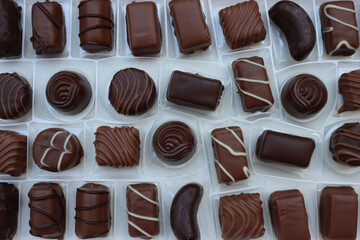 Close-up of inside of a white chocolate box with many assorted chocolate pralines