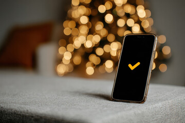 A smartphone displays a glowing ballot icon against a blurred background of warm, festive lights, symbolizing online voting and engagement in democratic processes