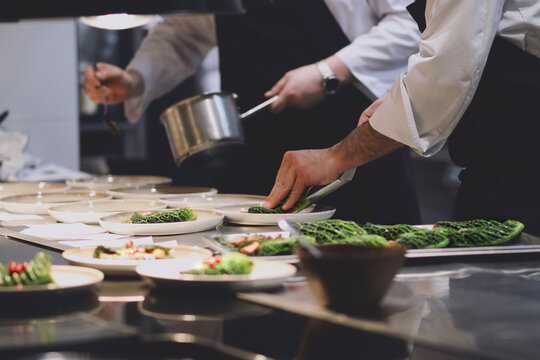 Chefs in a professional kitchen plating gourmet appetizers with precision, demonstrating teamwork and the final stages of a fine dining experience.