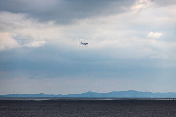 a flying airplane on mud flat beach and sea
