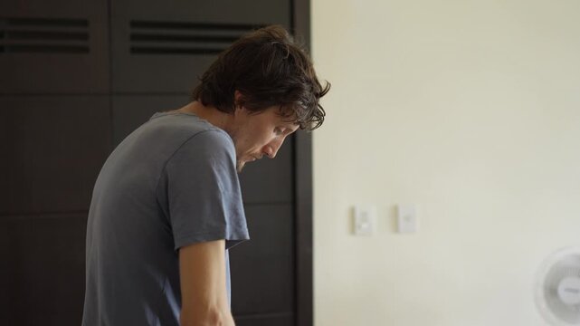 A young man is cooking food in the kitchen, focusing on preparing a delicious homemade meal. A relatable and warm moment of homemaking, creativity, and culinary enjoyment in a cozy setting.