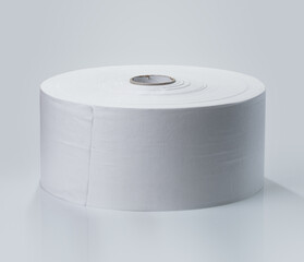A large roll of plain white paper sits upright on a neutral surface. The setting is bright, enhancing the clean and smooth texture of the paper.