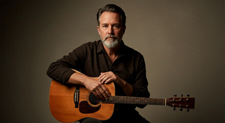 Studio portrait of a mature bearded musician sitting with an acoustic guitar