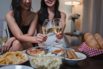Women toasting white wine, celebrating at home party