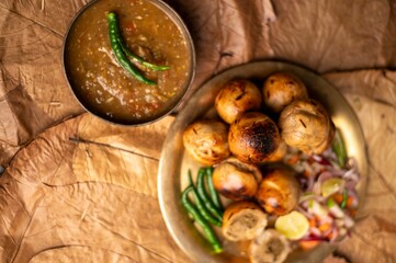 Litti Chokha is Bihar’s signature dish made with roasted wheat balls stuffed with spiced sattu, served with mashed potato, brinjal, and tomato. It reflects Bihar’s rustic flavors and culinary heritage