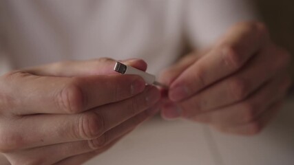 Close-up of technician hands inspecting and repairing damaged white lightning charging cable, highlighting expertise in electronics repair within workshop environment. Shooting in slow motion.