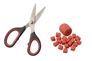 Scissors preparing red fishing bait into cubes