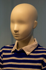 Close-up detail of a mannequin's face in a shop window with strong shadows and lights.