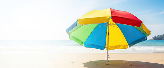 A colorful beach umbrella on a sandy beach with a clear blue sky.
