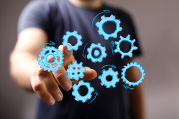 Abstract image of a hand interacting with digital gears, symbolizing teamwork, process, and technology.