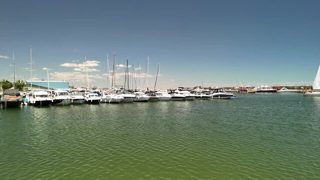 Side-to-side aerial drone view of marina with yachts and calm water in Constanta, Romania