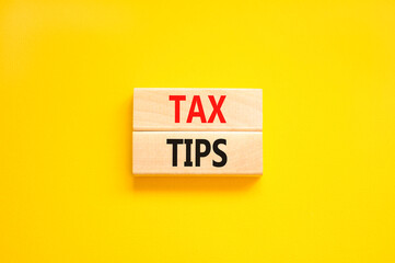 Tax tips symbol. Concept word Tax tips on beautiful wooden blocks. Beautiful yellow paper background. Business tax tips concept. Copy space.