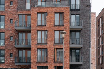 Fototapeta premium Modern brick apartment building showcases a mix of textures and colors in an urban setting with large windows and balconies designed for contemporary living