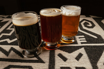 A group of glasses of Dark Craft Beer on a Traditional Andean Textile