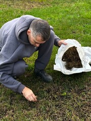 man collects weeded grass in a bag