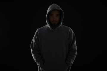 Criminal man in hood on dark background