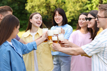 Group of happy friends clinking glasses of beer outdoors