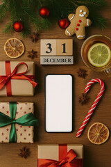 The wooden table is decorated for New Year's Eve on December 31. The scene features a blank smartphone screen for mockup purposes.