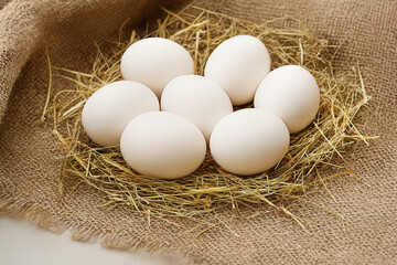 Seven clean eggs are gathered in a bed of straw. The rustic scene evokes feelings of farm life natural food and new beginnings.