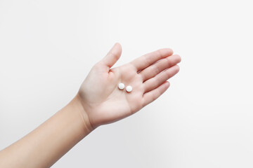 Hand holding two small round pills