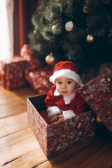Adorable Baby in Santa Outfit Sitting Inside Gift Box by Christmas Tree