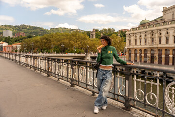 Obraz premium Young woman enjoying ice cream on bridge in san sebastian, spain