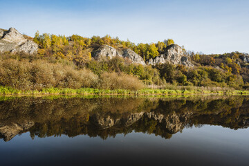 A Serene Autumn Landscape Beautifully Reflecting in the Calm Waters of the River, Showcasing the Tranquil Essence of Nature and the Idyllic Foliage During This Peaceful Season of Transition