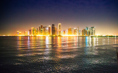 Beautiful night view of Doha city, skyscrapers of financial area and reflection in bay water. Qatar
