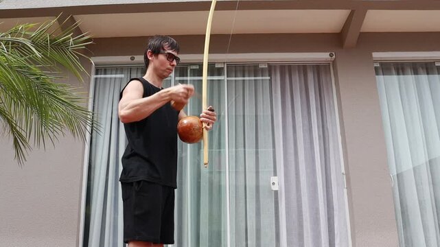 homem  toca instrumento de capoeira, cultura do brasil 