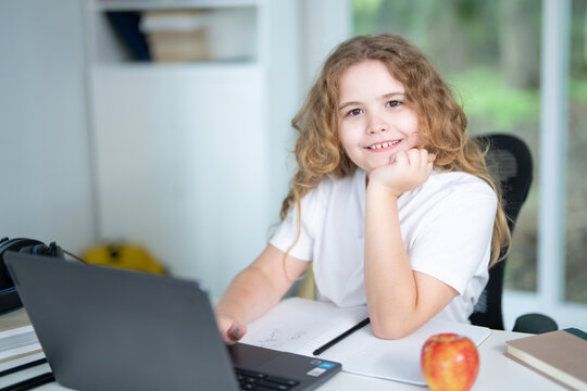 Kid using laptop for online studying at home. Child sitting at desk with laptop on virtual school lesson. Child learning with laptop. Young student . Kids watch online class on laptop.