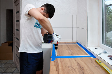 repairman using electric drill and installation new modern kitchen