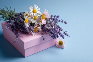 A bouquet of daisies and lavender sits on a pink box against a light blue backdrop