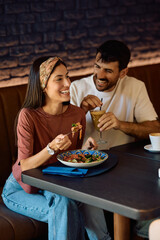 Happy woman having fun her boyfriend while eating in restaurant.