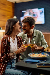 Affectionate couple toasting with wine in restaurant.
