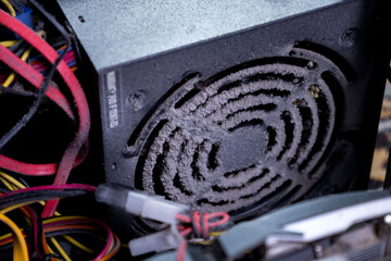Dust accumulation in computer power supply unit showing worn wires and dirty fan during hardware...