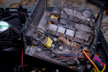 Dust accumulation inside an old computer power supply unit showing electronic components and wires...