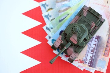 Bahraini dinar currency money bills and toy tank on flag. The concept of army funds and weapons