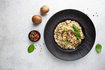 Risotto with mushrooms in a black plate over white background, top view