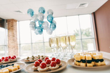Elegant corporate celebration event setup with appetizers, drinks, and decorative blue balloons in a spacious office setting