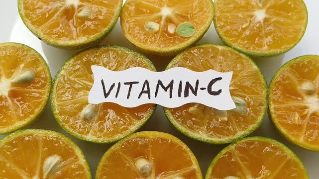 Vitamin c text or word calligraphy isolated on top of half slice ripe tangerine or orange. Closeup rotating top view. Vitamin c deficiency and citrus rich nutrient diet for healthy skin concept.