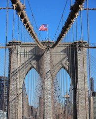 Fototapeta premium New York city with Large American Flag on the top of Brooklyn Bridge and steel cables