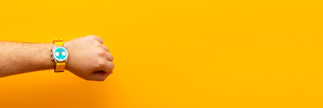 A striking ad banner showcasing a man hand wearing a stylish watch, set against a bold, energetic yellow background. time management ad creative yellow