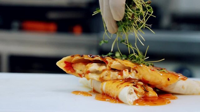 Delicious appetizer decorating with green. Chef's hand strewing pita by green sprouts before serving in the restaurant. Close-up. Slow motion.