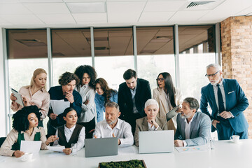 Diverse office team discussing a project together during a meeting in a modern workplace setting with laptops