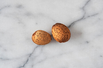 Close-up of almonds with their shells on white marble