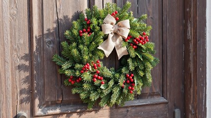 Naklejka premium Christmas wreath with red berries on wooden door