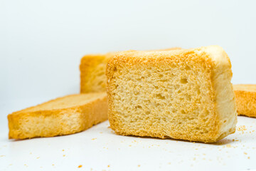 Several golden-baked Indian rusks are artfully arranged on a pristine white studio background. This close-up, minimalist composition emphasizes their crunchy texture and warm color.