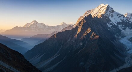 Majestic snow-capped mountains with hazy valleys under a soft, golden sky