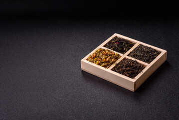 A wooden box with several types of dried tea, green, black, fruit, and chamomile. Dry tea in the box